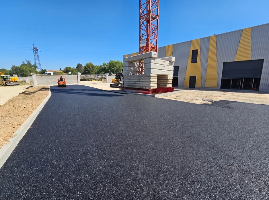 Chantier extérieur de voirie, pose d'enrobé bitumineux noir fraîchement compacté