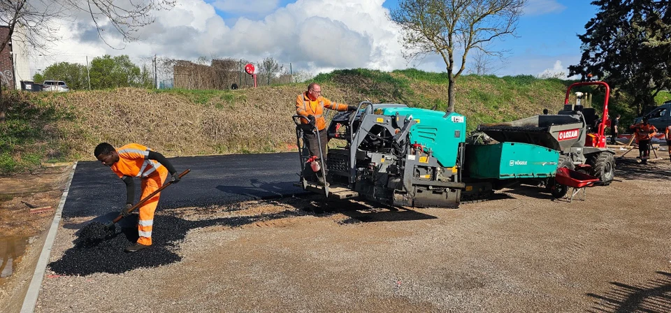 Chantier de travaux publics en milieu urbain avec ouvriers en équipement de sécurité haute visibilité effectuant des réparations de voirie
